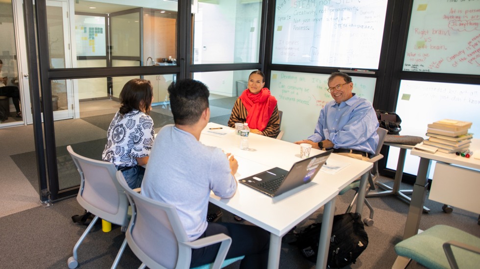 Members of the Brown community speaking together in a conference room