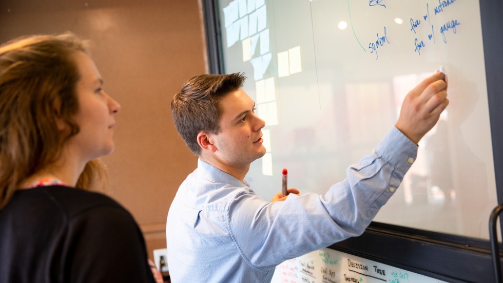 Brown community members working together at a whiteboard